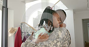 African American soldier father embraces a young daughter with braided hair and colorful beads