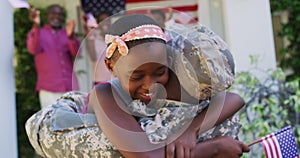 African american soldier father hugging smiling daughter with family and american flag behind