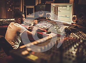 African american sound engineer working at mixing panel in boutique recording studio photo