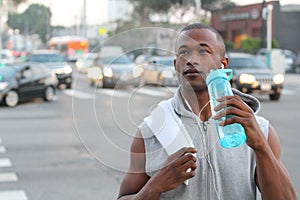 African American Sport man drinking water bottle in New York City. Male runner sweaty and thirsty after run