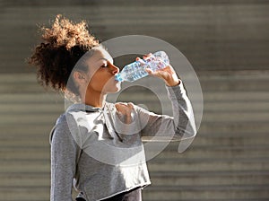 African american sports woman drinking from water bottle