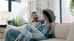 African American spouses couple man woman girl guy on sofa couch at home own apartment together talk discuss family