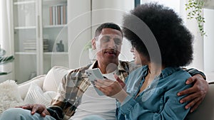 African American spouses couple man woman girl guy on sofa couch at home together talk discuss family shopping online