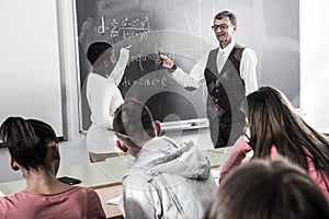 African-American student answers near blackboard at math lesson