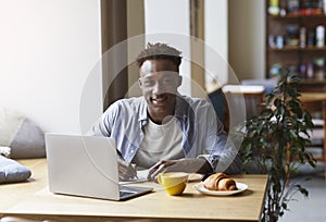 African American student with laptop doing homework in urban cafe