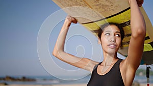 African american surfer standing with surf board on her head on ocean beach. Black woman looking at sea waves on lineup