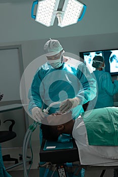 African american surgeon placing anaesthetic face mask on patient in operating theatre at hospital