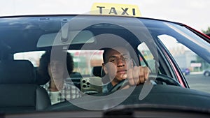 African American taxi driver driving with woman on the backseat. Yellow taxi car roof sign. People, job, service concept