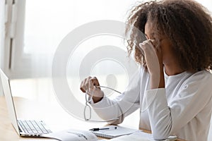 African American teen girl taking off glasses, feeling eye strain