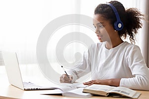 African American teen girl wearing headphones learning language online