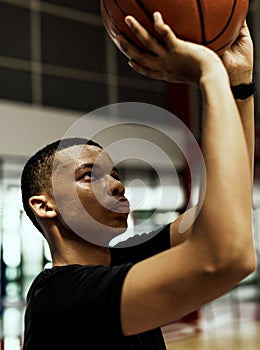 African American teenage boy concentrated on playing basketball