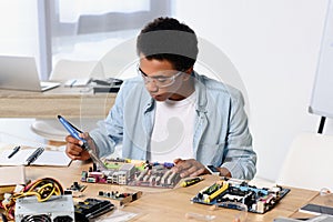 african american teenager soldering computer circuit with soldering iron