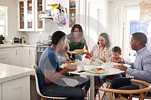 African American  three generation family sitting together at the kitchen table, with grandmother serving food