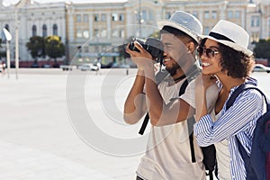 African-american tourist couple taking photos on camera on street