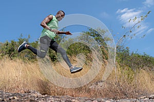 African american trail runner running on trail in natural mountain