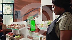 African american vendor holding phone with greenscreen