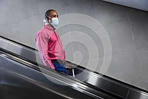 African American wearing covid19 coronavirus mask standing on escalator