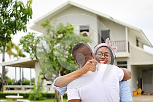 African American wife hugging her husband in front of the house they just move in while holding key for housing and relocation