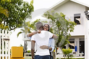African American wife hugging her husband in front of the house they just move in while holding key for housing, relocation and