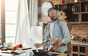 African-american wife kissing husband in kitchen