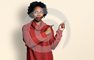 African american woman with afro hair pointing with fingers to the side smiling looking to the side and staring away thinking