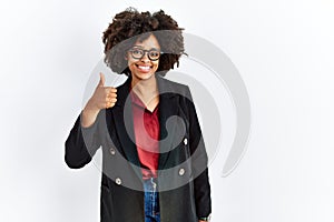 African american woman with afro hair wearing business jacket and glasses doing happy thumbs up gesture with hand