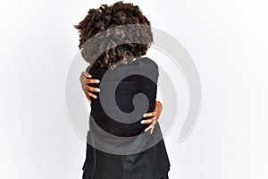 African american woman with afro hair wearing business jacket and glasses hugging oneself happy and positive from backwards