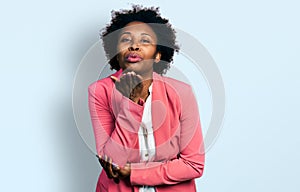 African american woman with afro hair wearing business jacket looking at the camera blowing a kiss with hand on air being lovely