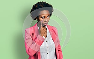 African american woman with afro hair wearing business jacket pointing to the eye watching you gesture, suspicious expression