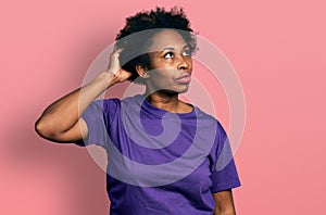 African american woman with afro hair wearing casual purple t shirt confuse and wondering about question
