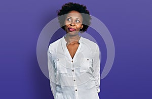 African american woman with afro hair wearing casual white t shirt smiling looking to the side and staring away thinking