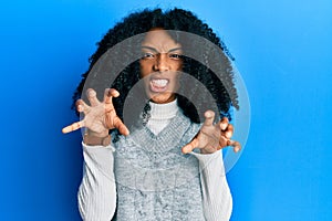 African american woman with afro hair wearing casual winter sweater smiling funny doing claw gesture as cat, aggressive and sexy