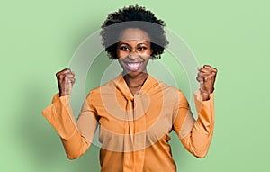 African american woman with afro hair wearing elegant shirt screaming proud, celebrating victory and success very excited with