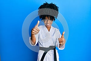 African american woman with afro hair wearing karate kimono and black belt approving doing positive gesture with hand, thumbs up