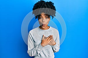 African american woman with afro hair wearing sportswear doing heart symbol with hands making fish face with mouth and squinting