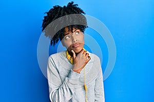 African american woman with afro hair wearing sweatshirt and using headphones serious face thinking about question with hand on