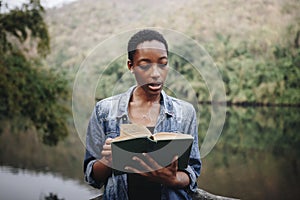 African American woman alone in nature reading a book leisure concept