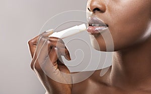 African american woman applying hygienic lip balm