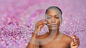 African american woman applying lip gloss