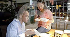 African American woman and Asian woman enjoy a business meal in the office