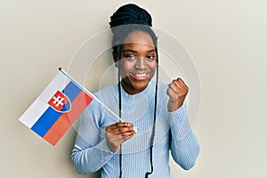 Afroameričanka so zapletenými vlasmi drží slovenskú vlajku, hrdo kričí, oslavuje víťazstvo úspech veľmi nadšená