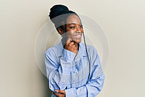 African american woman with braided hair wearing casual blue shirt thinking concentrated about doubt with finger on chin and