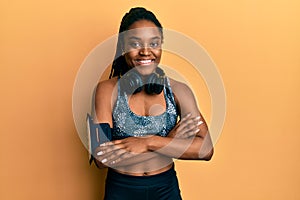 African american woman with braided hair wearing sportswear and arm band happy face smiling with crossed arms looking at the