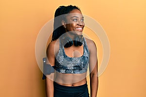 African american woman with braided hair wearing sportswear and arm band looking away to side with smile on face, natural