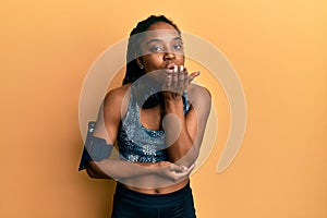 African american woman with braided hair wearing sportswear and arm band looking at the camera blowing a kiss with hand on air