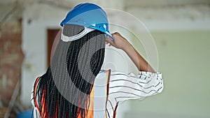 African american woman builder wearing hardhat standing backwards at construction site