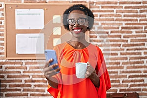 African american woman business worker using smartphone drinking coffee at office