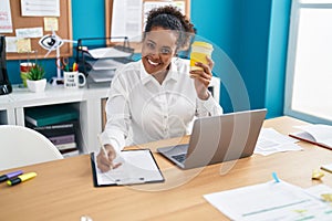 African american woman business worker writing on document drinking coffee at office