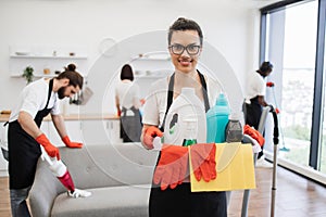 African American woman cleaning worker holding a bucket with detergents.