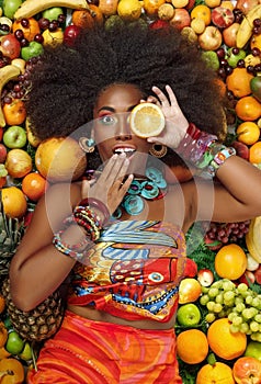 African American woman closing one eye with a slice of orange